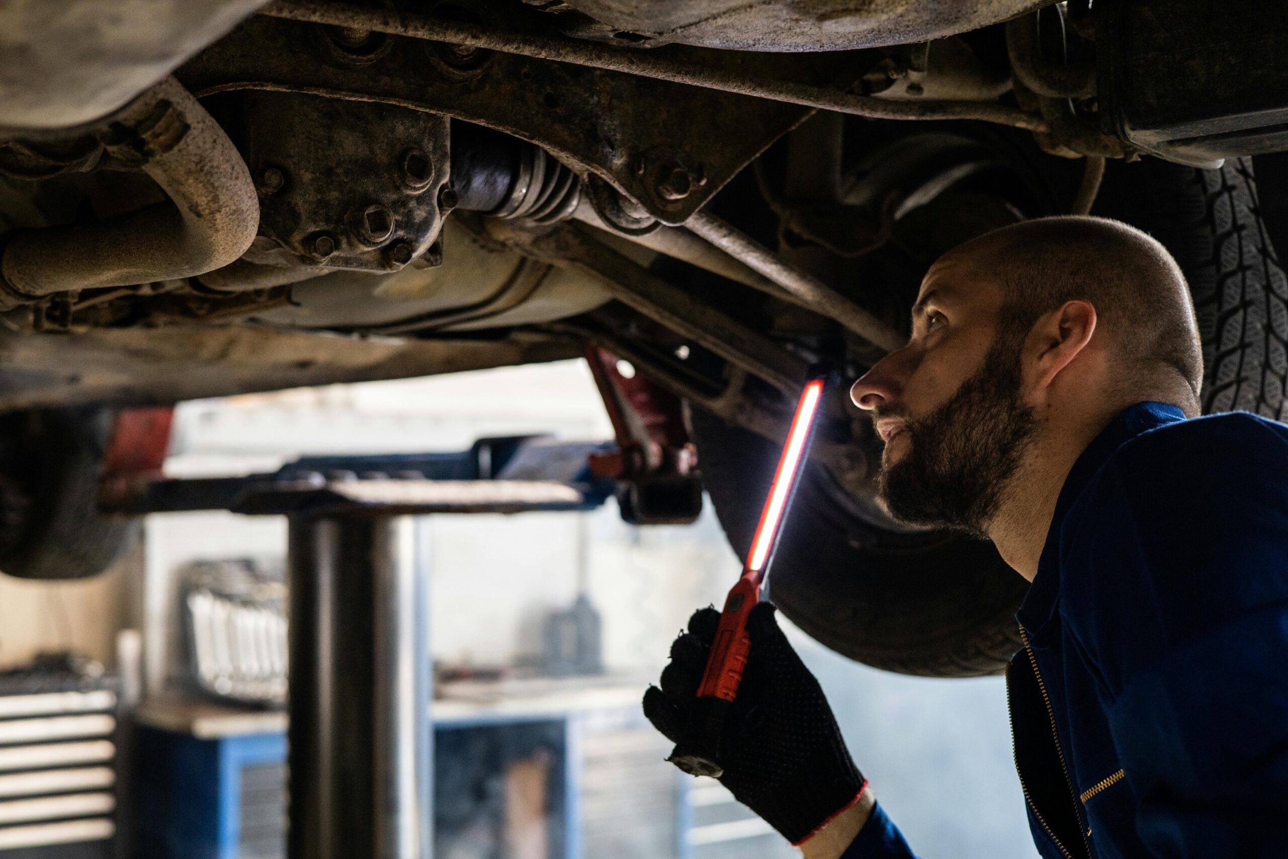 Mechanik z lampą LED inspekcyjną kontroluje podwozie pojazdu