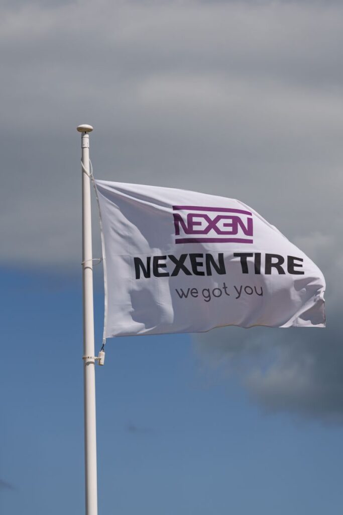Flaga Nexen Tire powiewająca na wietrze na tle zachmurzonego nieba
