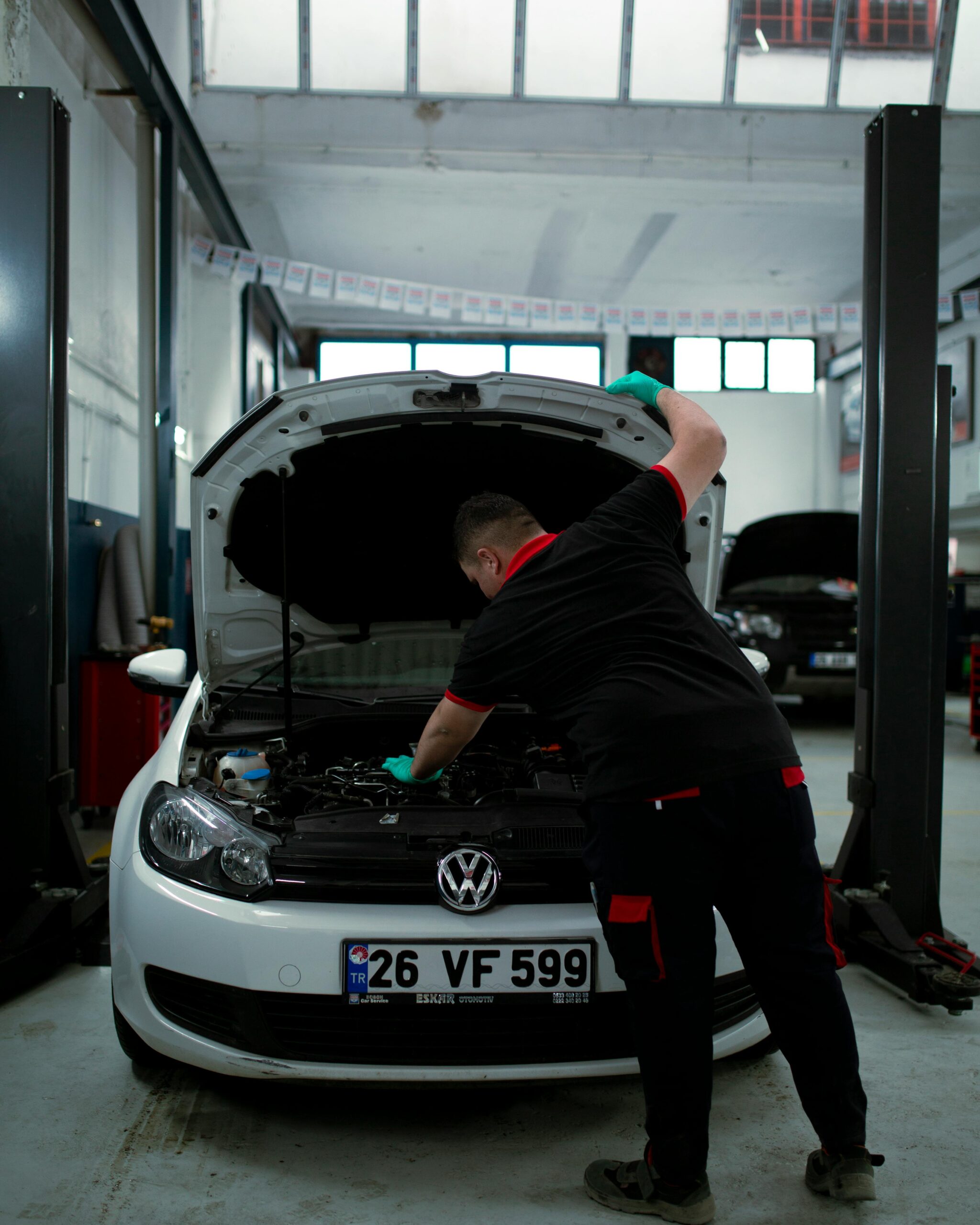 Mechanik samochodowy przy silniku Volkswagena Golfa w warsztacie