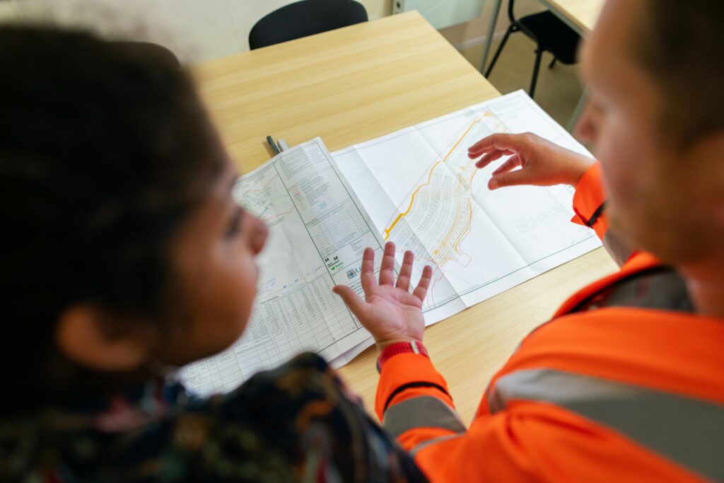 Dwoje pracowników w kamizelkach odblaskowych analizujących mapę tras