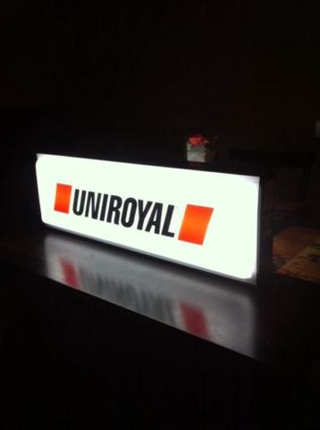 Podświetlana tablica reklamowa z logo Uniroyal na ciemnym blacie